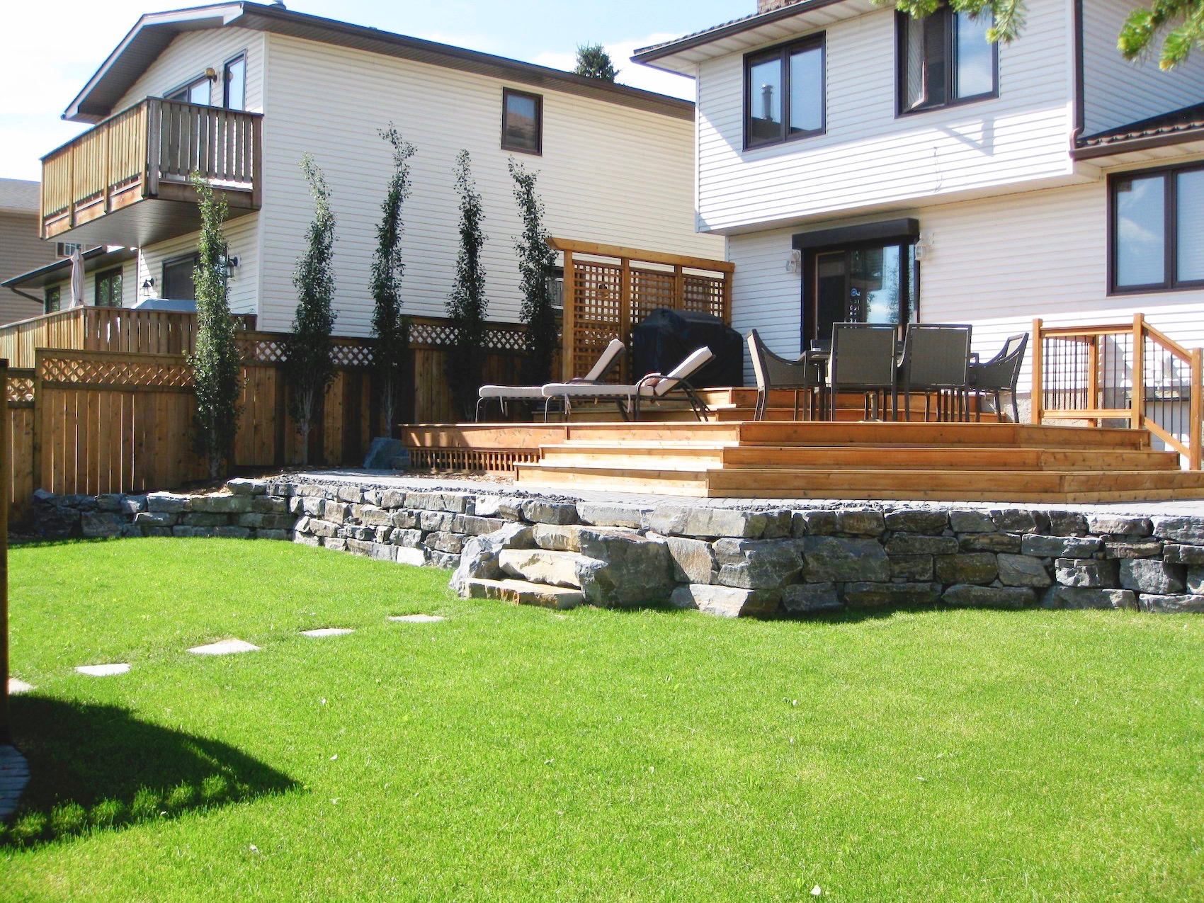 Multi-level cedar deck with stone retaining wall and lawn
